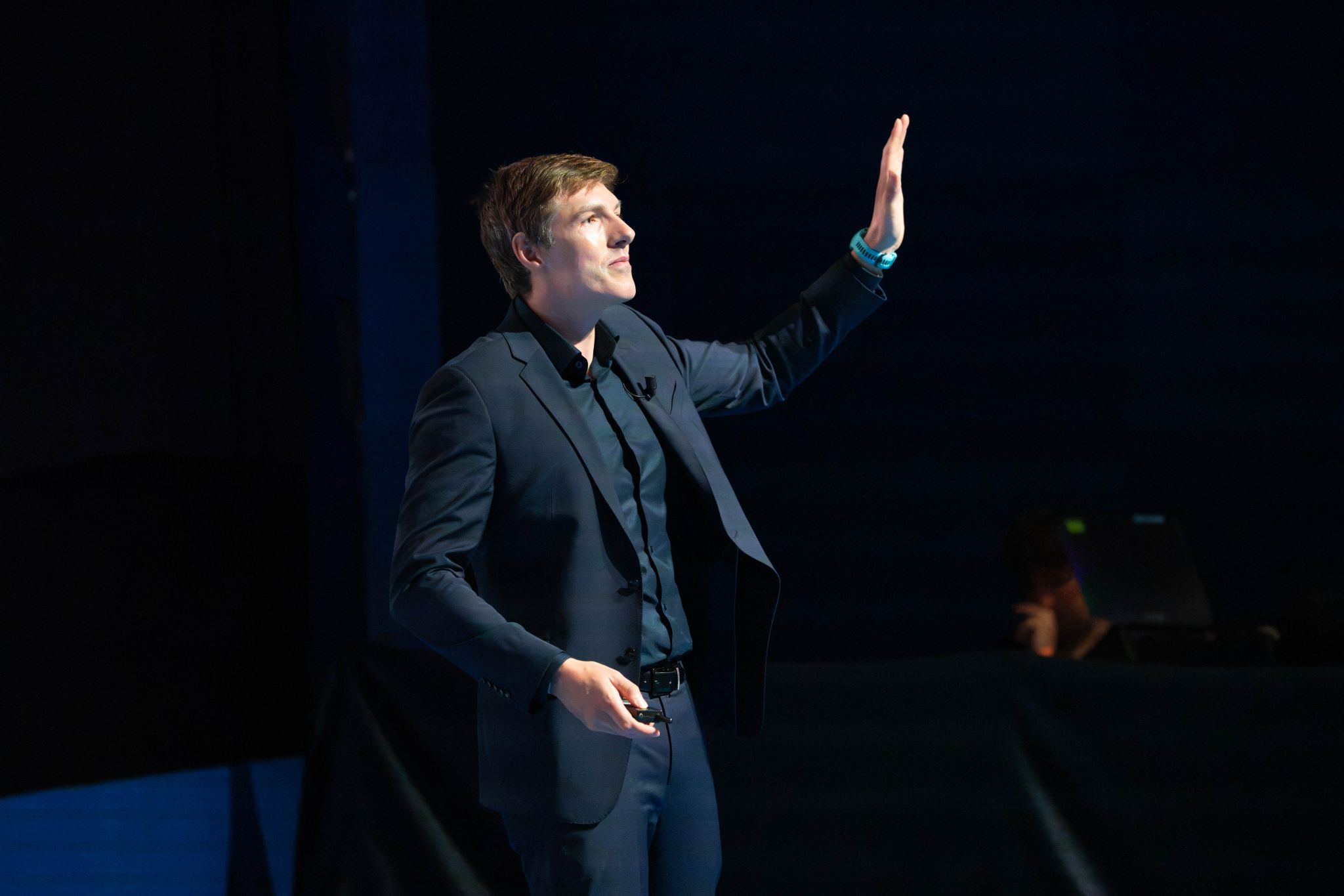 Mark Kelly speaking on stage with his hand raised during his keynote address at the Arrow TechNow Conference.